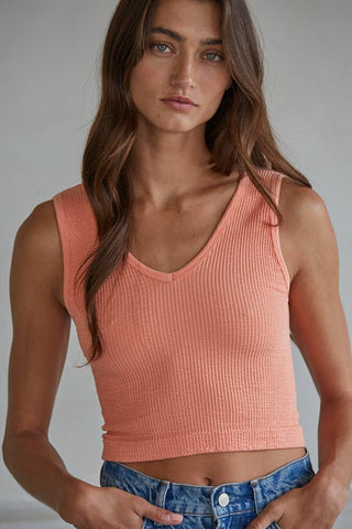Woman wearing a pink tank top against a neutral background