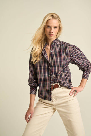 Woman wearing a plaid shirt and beige pants against a plain background