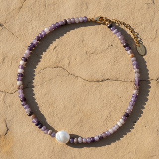 Beaded necklace with a large pearl on a beige stone surface