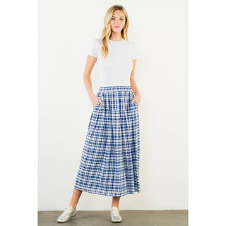 Woman wearing a white t-shirt and blue plaid skirt on a plain background