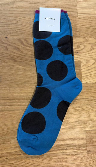 Blue sock with black dots on a wooden surface