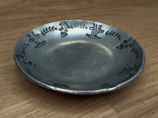 Silver plate with engraved design on a wooden floor