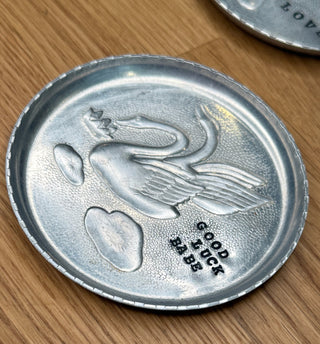 Silver coin with a design and text on a wooden surface