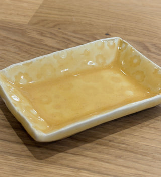 Rectangular ceramic dish with a yellow finish on a wooden surface