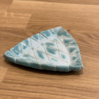 Triangular ceramic dish with a textured surface on a wooden floor