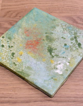 Decorative tile with floral pattern on a wooden surface