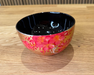 Ceramic bowl with black interior and pink floral exterior on a wooden surface