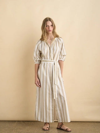 Woman wearing a long, light-colored striped dress against a beige background