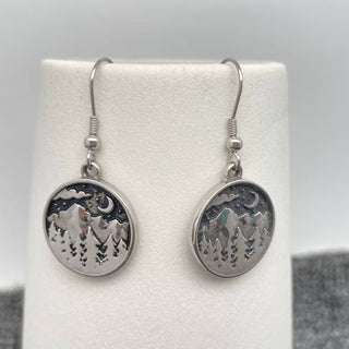 Silver earrings with engraved design on a white card