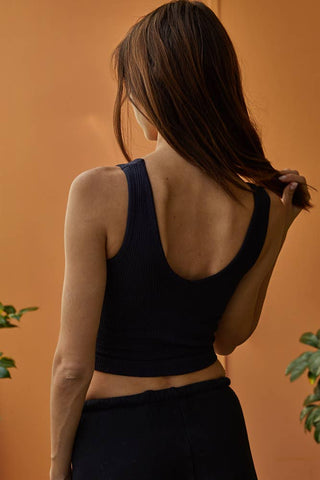 Woman wearing a black tank top against an orange background